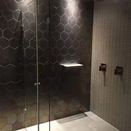 Northshore tiling service: Stylish bathroom project with bold black feature wall by Top End Tiling.