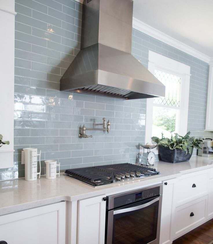 Modern Auckland kitchen featuring stylish grey subway splashback tiling that complements the white cabinetry and stainless steel range hood. The durable splashback tiling protects the walls above the countertop and gas stovetop.