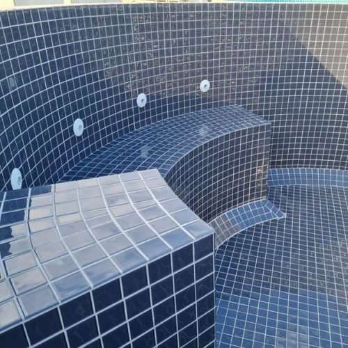 Top End Tiling Auckland: Stunning blue mosaic outdoor tiling around a swimming pool, perfect for NZ landscapes.