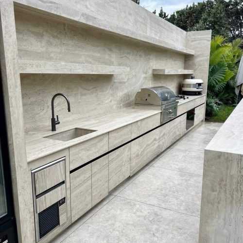 Stylish outdoor kitchen featuring seamless outdoor tiling on the countertops, backsplash, and flooring, creating a cohesive and durable entertaining space in Auckland, New Zealand.
