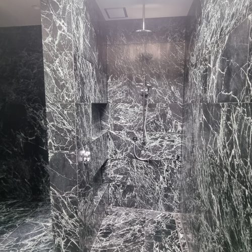 Professional bathroom tilers created this flawless natural stone installation with a 1/3 break pattern and sharp mitre edges.